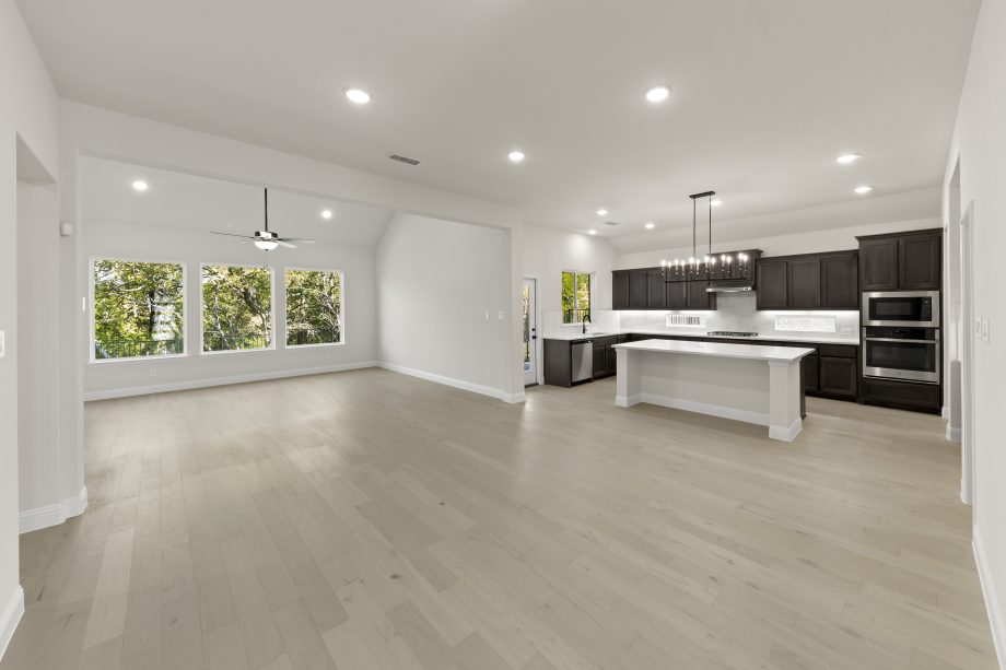 Open concept family room and kitchen with large windows, stained cabinetry, quartz countertops, large kitchen island. This floor plan is perfect for entertaining.