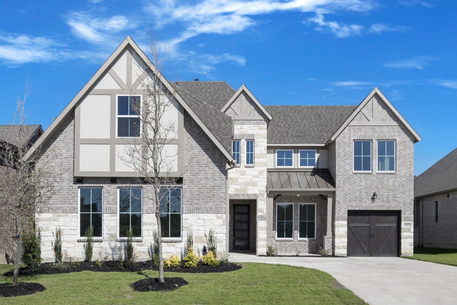 Preston floor plan exterior showcasing a two-story design with brick and stone detailing, front-entry garage, and landscaped yard.